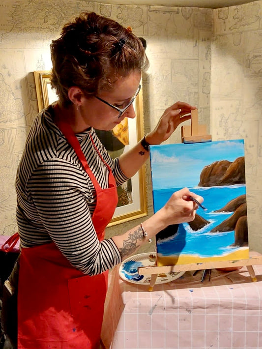 Effy the Artist painting a landscape image with acrylic at one of her paint and sip nights